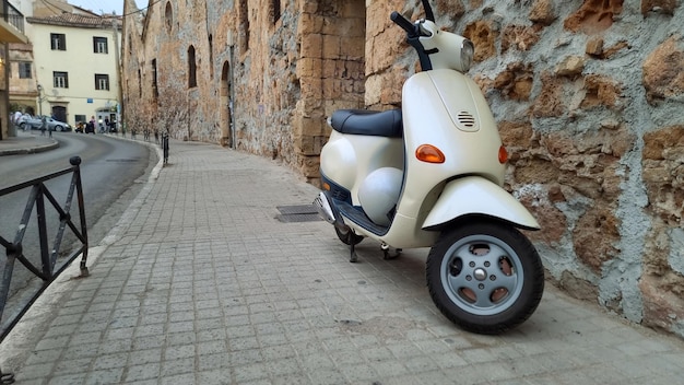 市内舗装された歩道に駐車した白いレトロスクーターヘルメットをかぶった新しいオートバイ