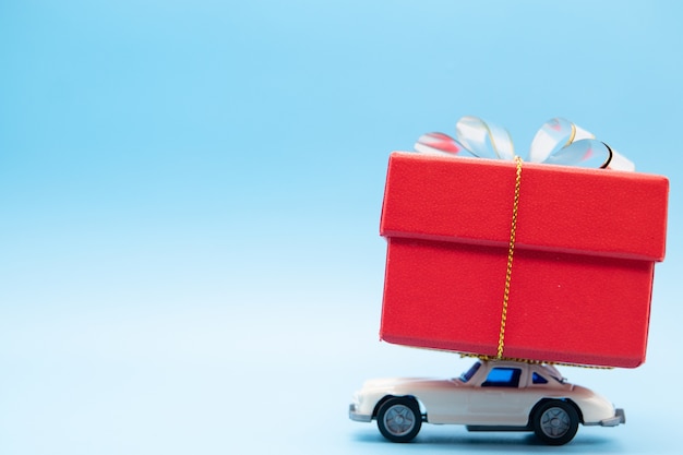 Photo white retro toy car delivering a big red gift box