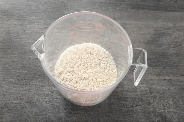 White rice in measuring cup on table