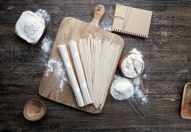 White rice noodles and flour and other ingredients cooking rice noodles on a wooden table closeup