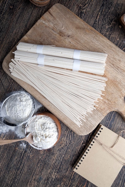 White rice noodles and flour and other ingredients cooking rice noodles on a wooden table closeup