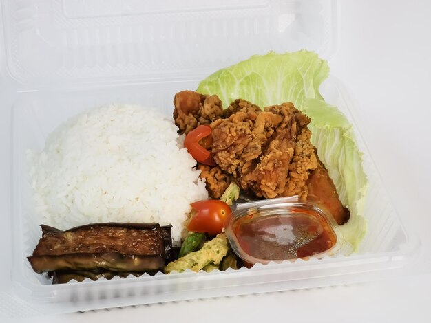 White rice with fried chicken and chili paste also known Nasi Katok in plastic container.