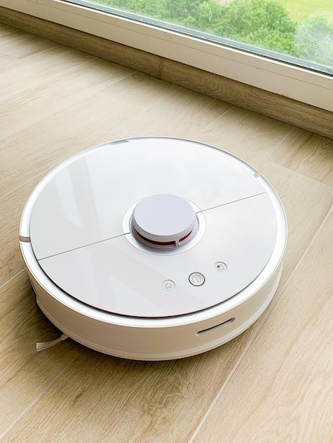 White robot cleaner robot vacuum cleaner on laminate floor in action