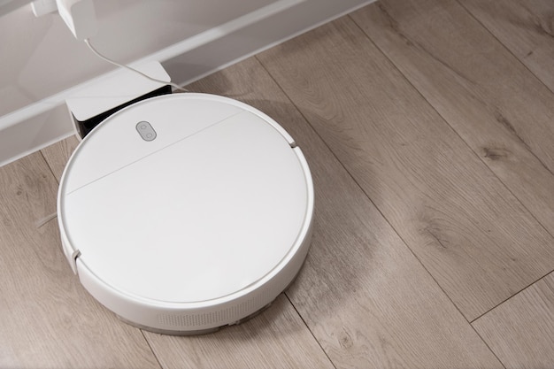 White robot vacuum cleaner stands at the charging station