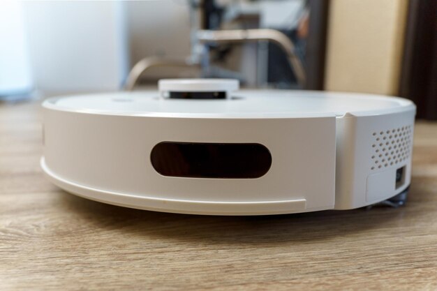 White robotic vacuum cleaner on linoleum floors smart cleaning technology Selective focus