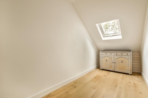 Photo a white room with wood floors and a small cabinet in the corner on the right is an open skylight window