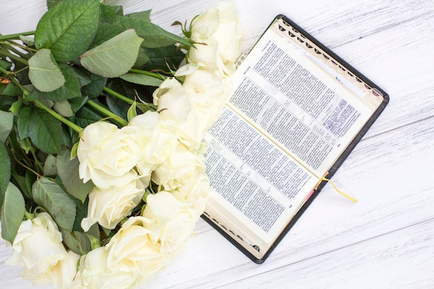 White roses and the bible. white roses and the bible on a white wooden background