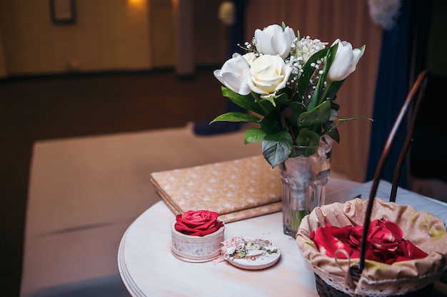 White roses bouquet in glass jar on gray table runner and kitchen table.