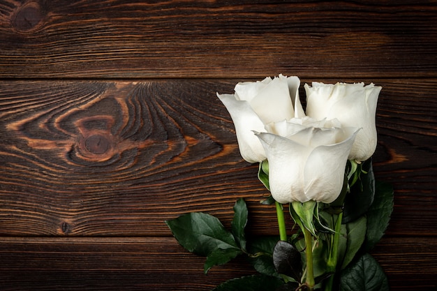 White roses on dark wooden table.