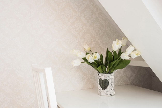 White roses Flower Arrangement in a vase on a desk in a white modern room