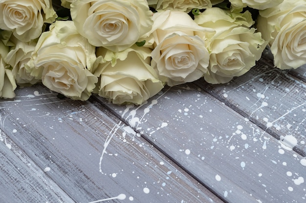 灰色の木製の背景に白いバラ。コピースペース。