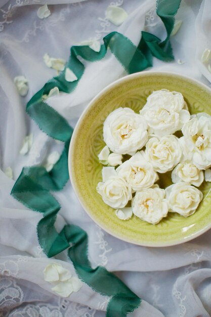 녹색 그릇에 흰색 장미와 흰색 천에 녹색 실크 리본 꽃과 리본 장식