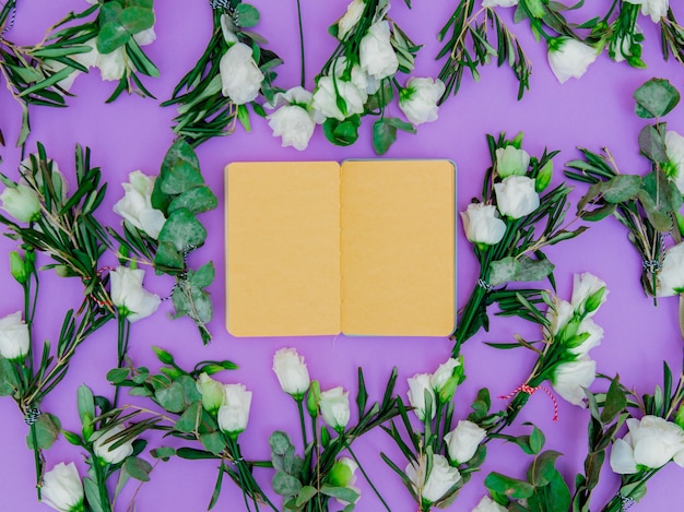 Белые розы и рецепт ноутбука на фиолетовом фоне. Вид сверху