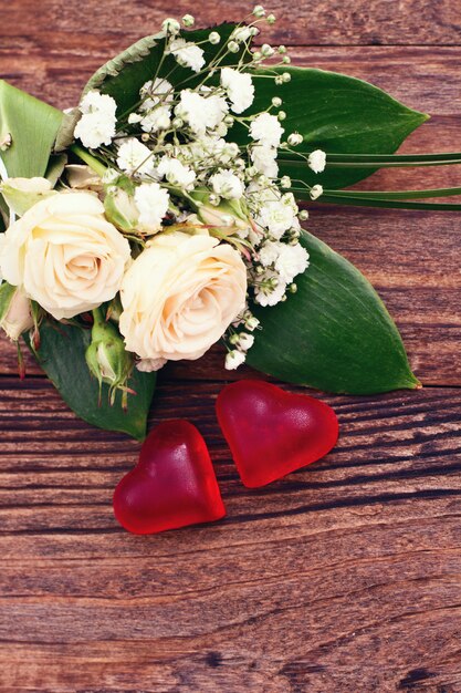 White roses and wedding hearts on wooden texture