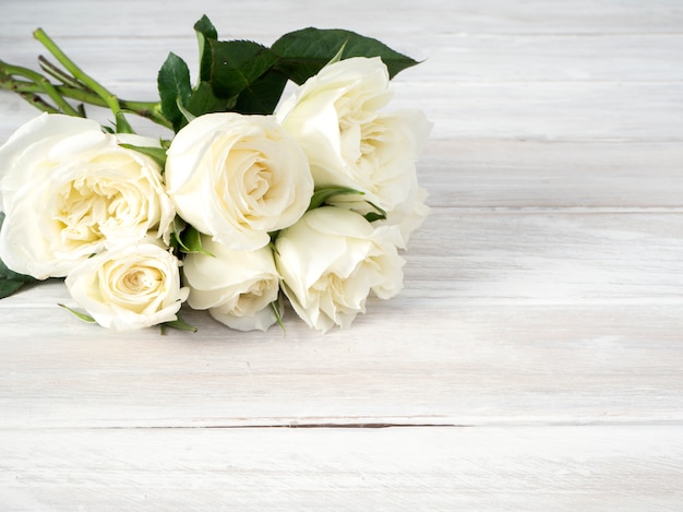 白い木製のテーブルの上の白いバラ