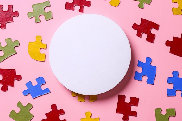 Фото Белый круглый пьедестал с цветовой головоломкой, символом осведомленности о расстройстве аутистического спектра на розовой спине