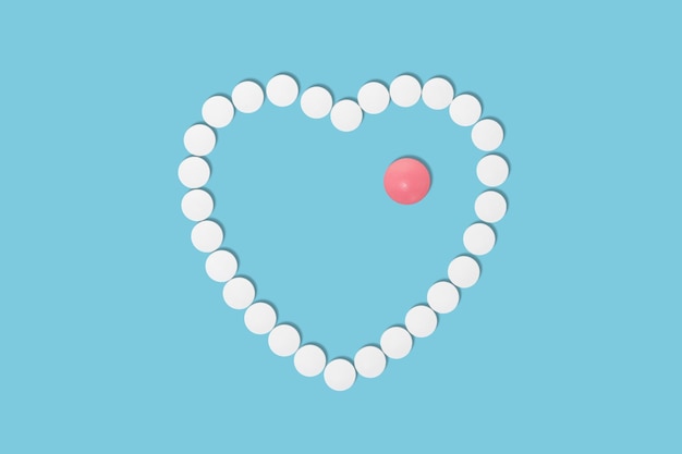 White round pills create a heart shape on a blue background and a red pill inside