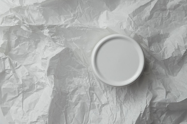 Barattolo di plastica rotondo bianco per crema cosmetica mockup su sfondo bianco di carta stropicciata