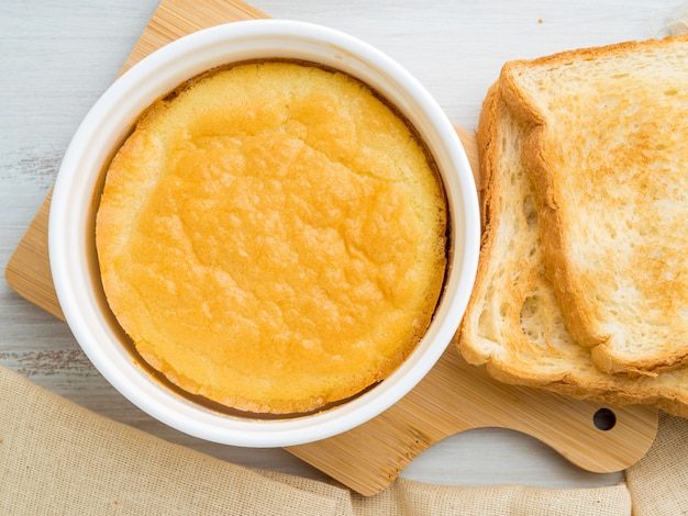 White round ramekin with oven-baked omelet of eggs and milk, with a crust, on white wooden