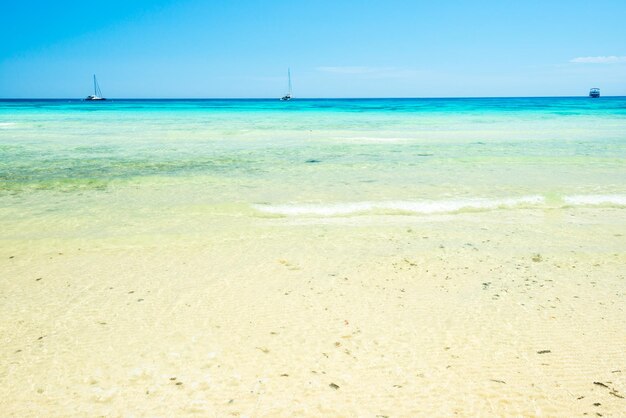 写真 白い砂浜と青い空の下の澄んだ海の水。夏休みの背景として使用できます