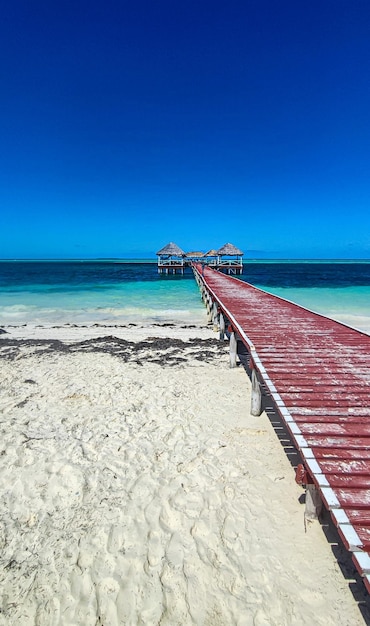 White sand beach atlantic ocean with wooden pier and huts on a sunny day tropical seascape