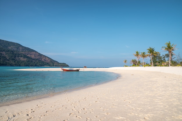Фото Белый песчаный пляж с деревянным длиннохвостым катером в тропическом море