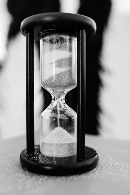 Photo white sand hourglass in brown wood on table