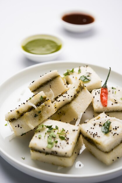 White Sandwich Dhokla is an Indian savoury snack made of chick pea flour or rice flour, Originated in Gujarat. Served with green and tamarind chutney. selective focus