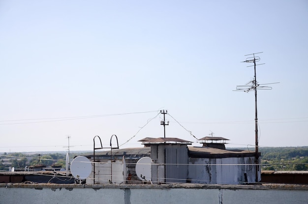 White satellite dishes with two converters mounted on residental building rooftop concrete wall Satellite television