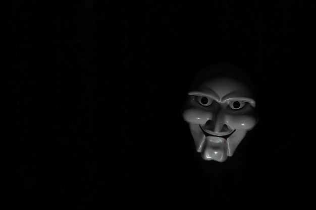 White scary mask on a black background with whites hands.