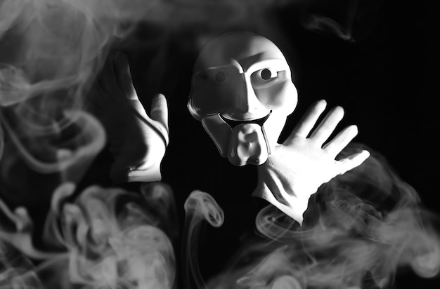 White scary mask on a black background with whites hands.