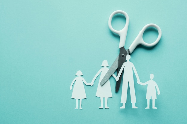 White scissor cutting family paper cut out on blue background