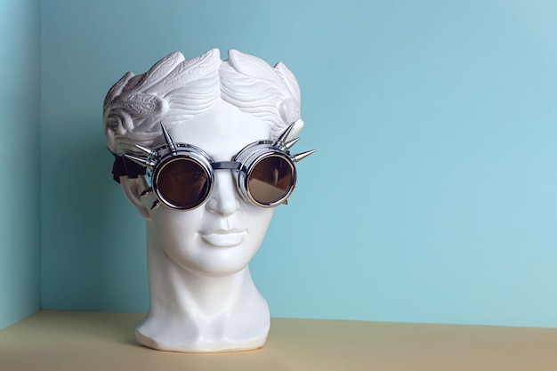 White sculpture of an antique head in rock glasses.