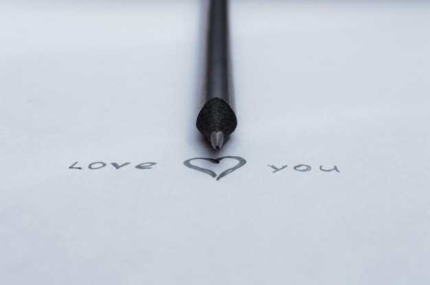 On a white sheet of paper in pencil is written LOVE YOU