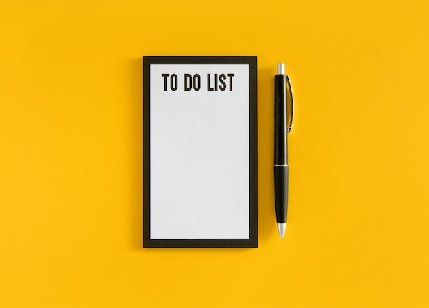 White sheet with to do list phrase and black pen on yellow background stock photo