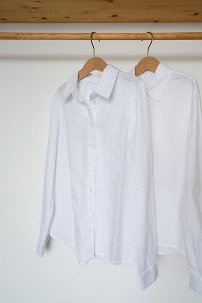 White shirt hanging on wooden hanger on white wall background