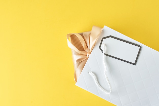 White shopping bag with gift box on blue, top view