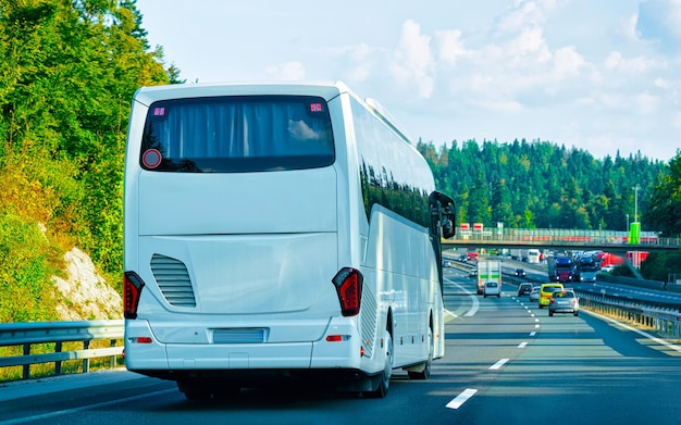 White Shuttle bus back in road, Poland. Modern public transport traffic and Summer drive. Charter coach vehicle on Vacation trip. Holiday journey for recreation. Motion and urban ride.