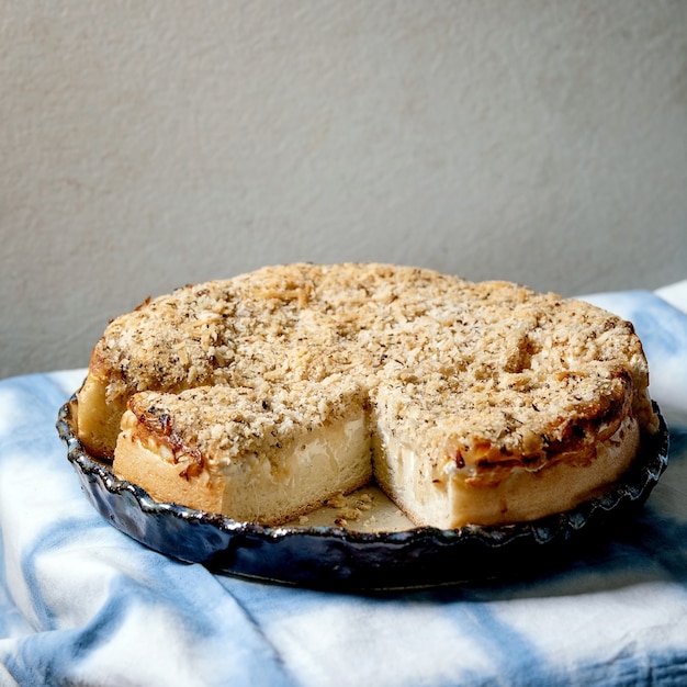 White sicilian focaccia. traditional baked bread sliced cake with onion, herbs and cheese in ceramic dish served on blue and white tablecloth. square image