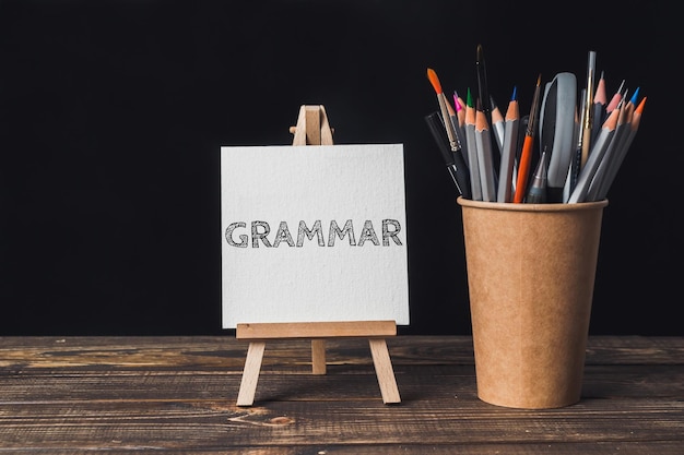 A white sign with the word Grammar written on it is on a wooden table