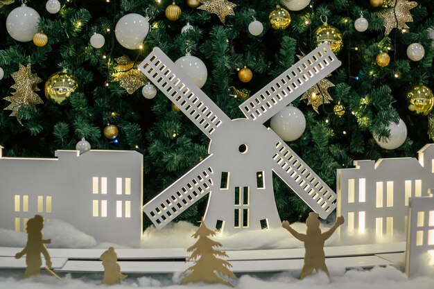 White silhouettes of windmill and houses, against background of decorated Christmas tree