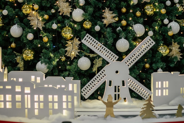 White silhouettes of windmill and houses, against background of decorated Christmas tree