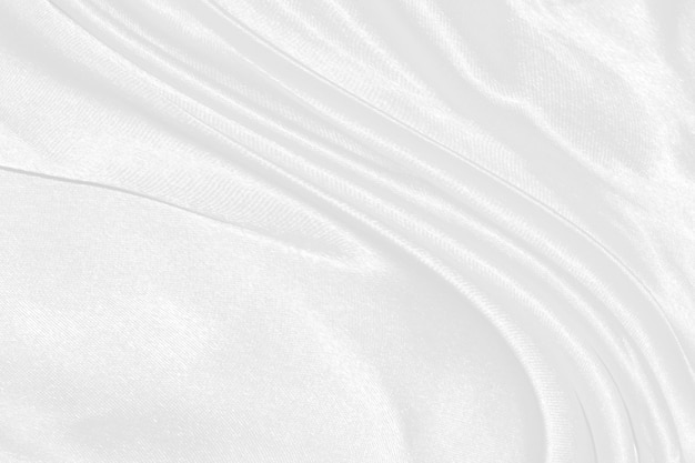 白い絹の織り目加工の布の背景柔らかい波と波状のサテン生地のクローズアップ