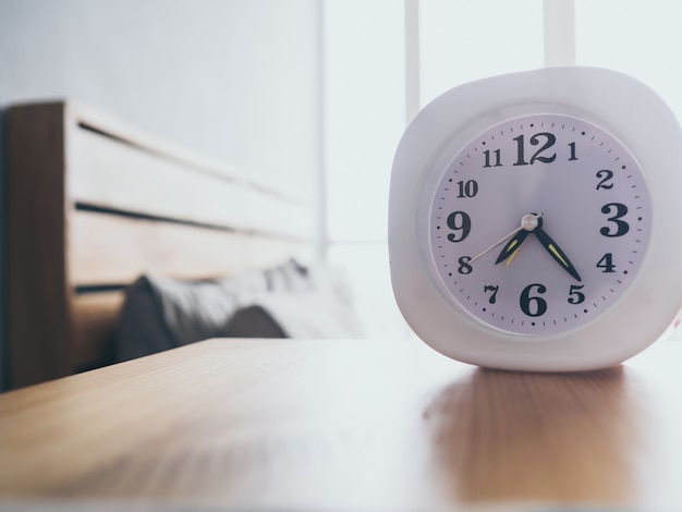 Foto bianco semplice orologio sul loft woden letto al mattino.