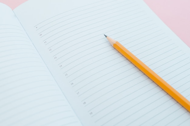 White sketch book with orange pencil. Note book and pencil