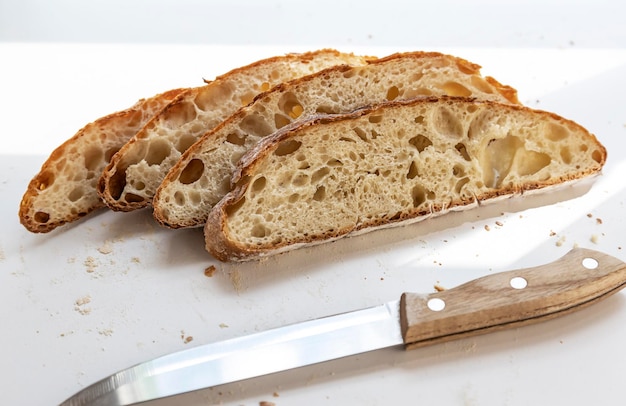 Белый нарезанный хлеб и нож Четыре ломтика нарезанного хлеба