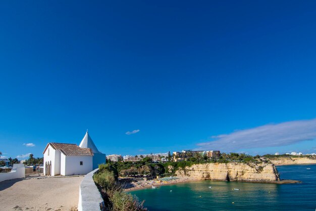 White small church on top of cliff at Armacao de Pera beach Algarve region Portugal