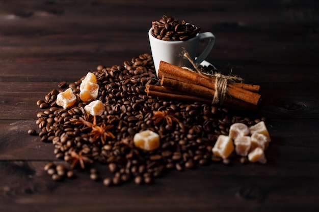 White small coffee cup filled with freshly roasted dark coffee beans