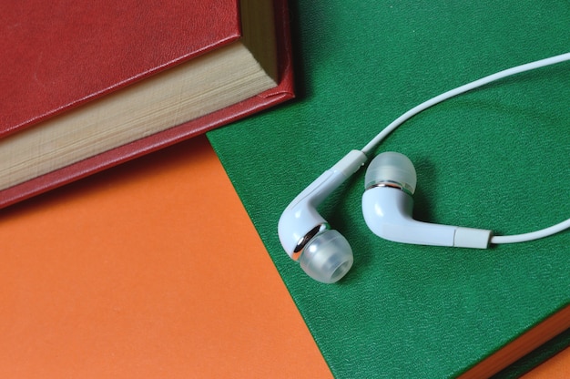 White small earphones and stack of books audiobook concept.