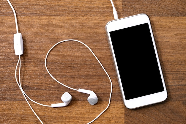 White smart and earphones on wood background